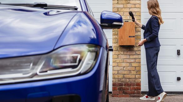 Woman charging an electric car at a home station, promoting sustainability.