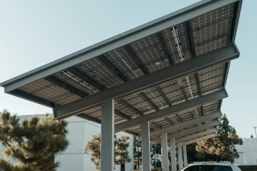 Cars parked under solar panel structures in a modern parking lot utilizing renewable energy.